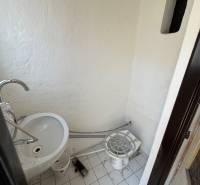Ein kleiner Innenraum mit Waschbecken und weißen Fliesen in Geschäftsräumen.