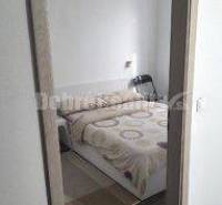Ein Zimmer mit einem eingebauten Bett und einem Nachttisch in einer Zweizimmerwohnung.