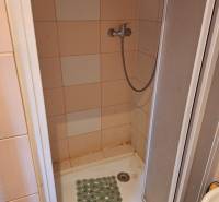 Duschkabine in einer Einzimmerwohnung mit Fliesen und einem Wasserschlauch.