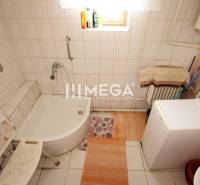 Badezimmer in einem Einfamilienhaus mit Badewanne, Waschmaschine und einer mit Fliesen bedeckten Wand.