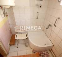 Badezimmer in einem Einfamilienhaus mit gefliesten Wänden und Duschwanne.
