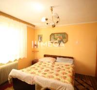 Schlafzimmer in einem Einfamilienhaus mit Bett, Bildern und gelben Wänden.