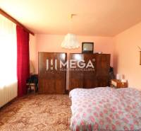 Schlafzimmer im Einfamilienhaus mit Schrank, Fernseher, großem Fenster und Bett.