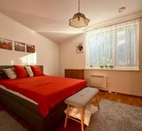 Ein Schlafzimmer in einem Einfamilienhaus mit einem roten Bett, einem Kleiderschrank und einem großen Fenster.