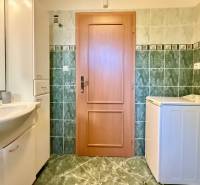 Badezimmer mit Waschmaschine, Waschbecken und Fliesen in einem Einfamilienhaus.