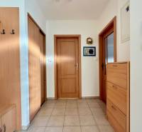 Ein Flur in einem Einfamilienhaus mit Holzmöbeln und Fliesenboden.