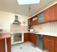 Küche in einem Einfamilienhaus mit Holzschränken, Geschirrspüler und Keramikfliesen an der Wand.