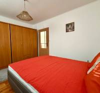Schlafzimmer mit einem Holzschrank, einem roten Bett und einer Deckenleuchte in einem Einfamilienhaus.