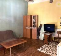 Wohnzimmer mit Sofa, Schrank und Fernseher in einem Einfamilienhaus, einfache Einrichtung.