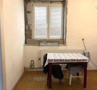 Ein Zimmer eines Einfamilienhauses mit einem Fenster, einem Tisch und Stühlen, einfaches Interieur.