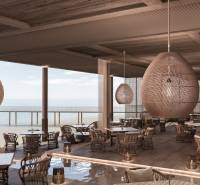Ein luxuriöses Restaurant mit Blick auf den Ozean, stilvolle Hängeleuchten, komfortable Sitzgelegenheiten.