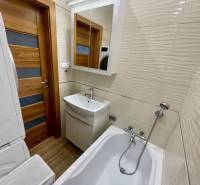 Badezimmer in einer 4-Zimmer-Wohnung mit Waschmaschine, Badewanne, Waschbecken und Spiegel.