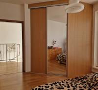 Innenraum eines Einfamilienhauses mit Einbauschrank, Spiegel und Leopardenmustern auf dem Bett.