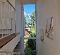Innenraum eines Einfamilienhauses mit großem Fenster, Blick in den Garten und Treppe.