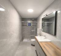 Badezimmer mit Dusche und Waschbecken in einer 4-Zimmer-Wohnung, helle Fliesen.