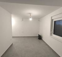 Ein leerer Raum in einer Vierzimmerwohnung mit weißen Wänden und grauem Boden.