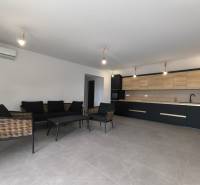 Wohnbereich einer 4-Zimmer-Wohnung mit dunklen Möbeln und einer Küche mit Holzelementen.