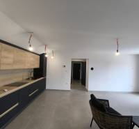 Innenraum einer 4-Zimmer-Wohnung mit minimalistischer Küche und schwarzem Sessel im Wohnzimmer.