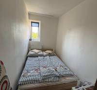 Ein kleines Schlafzimmer mit einem Bett in einer 3-Zimmer-Wohnung, einfache Einrichtung und weißes Interieur.