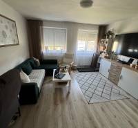 Wohnzimmer in einer 3-Zimmer-Wohnung mit Sofa, Tisch, Fernseher und Teppichboden.