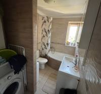 Badezimmer mit Waschmaschine, Badewanne und Waschbecken in einer 3-Zimmer-Wohnung.