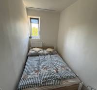 Ein kleines Schlafzimmer mit einem schmalen Fenster und einem Bett in einer 3-Zimmer-Wohnung.