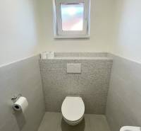 Badezimmer in einem Einfamilienhaus mit Keramikfliesen und Toilette.