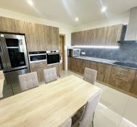 Küche eines Einfamilienhauses mit Holzmöbeln und eingebauten Geräten.