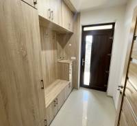 Eingangsbereich mit Holzmöbeln in einem Einfamilienhaus, enthält Stauraum und Eingangstür.