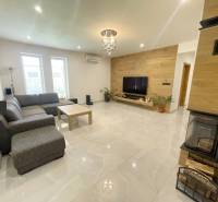 Wohnzimmer in einem Einfamilienhaus mit Kamin, Ecksofa und Fernseher an der Holzwand.
