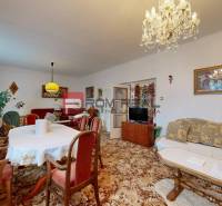 Wohnzimmer in einem Einfamilienhaus mit Möbeln, Teppich, Kronleuchter, Vorhängen und Bildern.