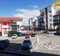 Parkplatz in der Slavomírova-Straße mit Autos vor Gebäuden in einer städtischen Umgebung.