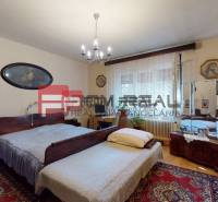 Schlafzimmer im Einfamilienhaus mit Holzmöbeln, Teppich und Bildern.