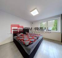 Ein Schlafzimmer in einem Einfamilienhaus mit einem Doppelbett, dunklen Möbeln und großen Fenstern.