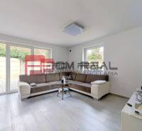 Wohnzimmer in einem Einfamilienhaus mit Sofa, Fenstern und Fernseher.