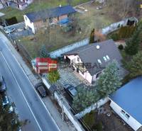 Ein Einfamilienhaus in Píla an der Straße, mit zwei Autos und einem gepflegten Garten.