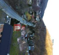 Einfamilienhäuser im Dorf Píla, gesäumt von Straße und Wald.