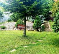 Garten bei einem Einfamilienhaus in Píla mit Rasen, Bäumen und Steintreppen.