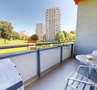 Der Balkon einer Einzimmerwohnung in der Koprivnická 9/F in Bratislava IV mit Blick auf Grünflächen und Plattenbauten.