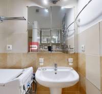 Badezimmer in einer Einzimmerwohnung mit Waschbecken, Spiegel, Waschmaschine und Handtuchheizkörper.
