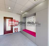 Innenraum eines Büros mit einer Garderobenwand, einer rosa Bank und Brandschutzausrüstung.
