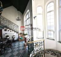 Innenraum eines Gebäudes mit dekorativer Treppe in der Ľ. Podjavorinská-Straße, große Fenster lassen Licht herein.