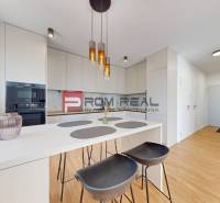 Küche in einer 2-Zimmer-Wohnung mit weißer Theke und Stühlen.