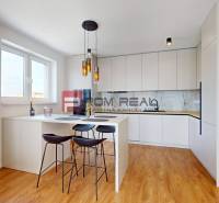 Küche in einer 2-Zimmer-Wohnung mit Bartresen, Stühlen und eingebauten Geräten.