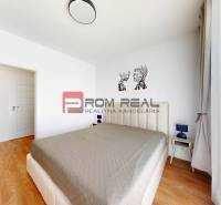 Schlafzimmer in einer 2-Zimmer-Wohnung mit einem großen Bett, Nachttischen und Bildern an der Wand.