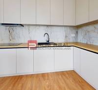 Küche in einer 2-Zimmer-Wohnung mit hellen Schränken und Holzboden.