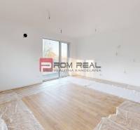 Helles Zimmer mit großen Fenstern und Holzboden in einer 2-Zimmer-Wohnung.
