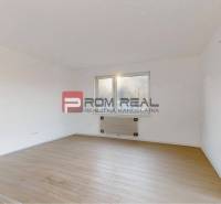 Ein Zimmer in einer 2-Zimmer-Wohnung mit weißen Wänden und Holzboden.