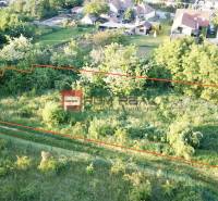 Ein Baugrundstück in der Poľná-Straße in Budmerice, umgeben von Grünflächen und Nachbarhäusern.