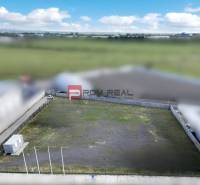 Produktionsräume in Pezinok mit leerem eingezäuntem Grundstück und Containerobjekt.